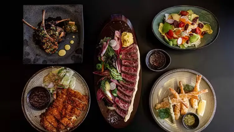 An overhead spread of Yamasaki dishes — sliced steak, sashimi, salad and tempura
