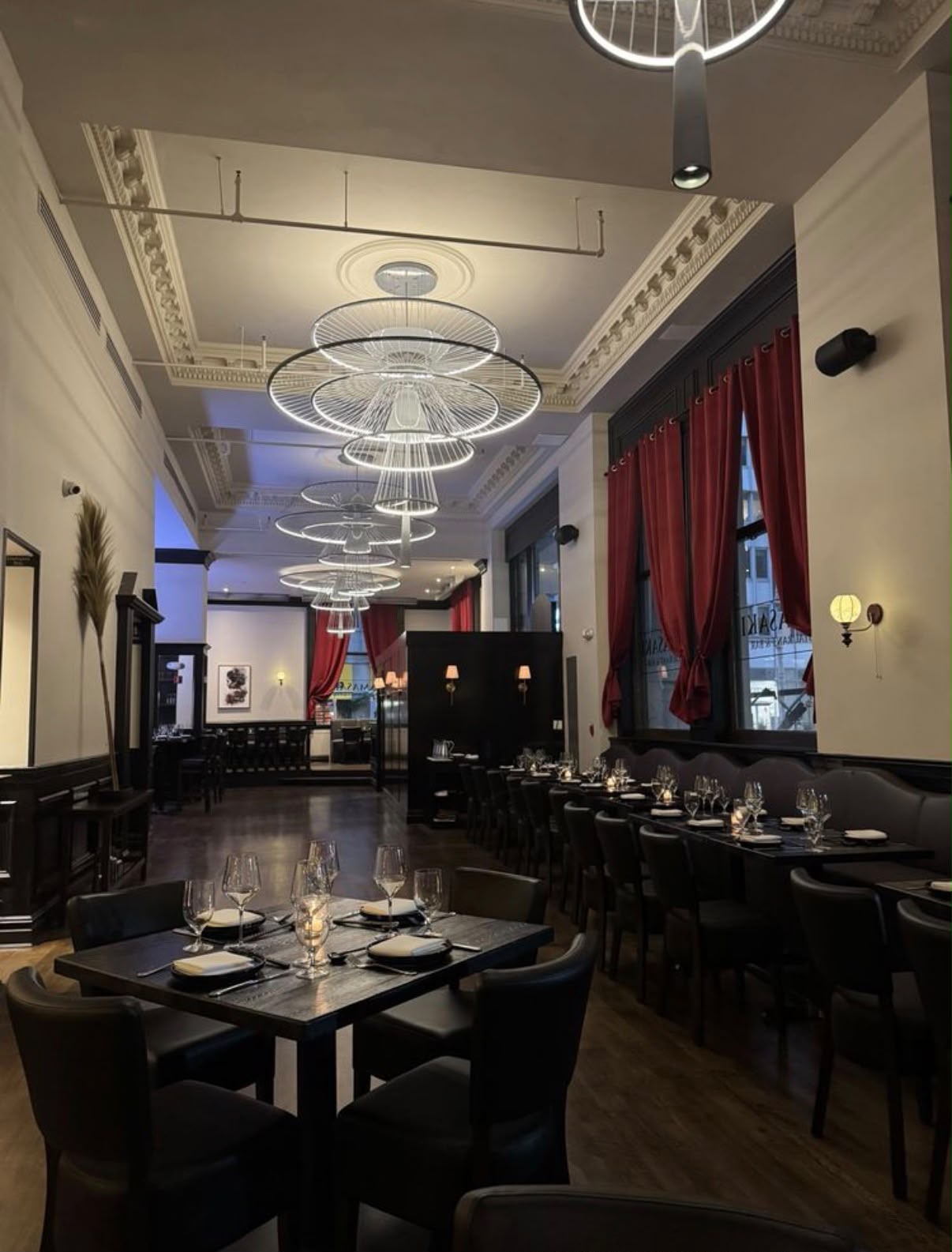 The Yamasaki dining room at night, with sculptural ring chandeliers and deep red drapery